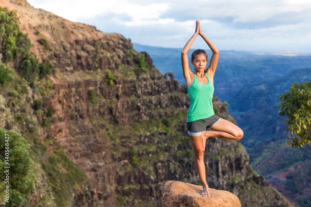 Woman doing yoga in Hawaii mountains. Asian girl meditating in