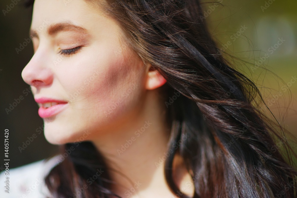 Portrait of a dreamy beautiful woman meditating outdoors with eyes closed, with the effect of blur on a dark background closeup. Portrait of a dreamy beautiful woman meditating outdoors with eyes closed, with the effect of blur on a dark background closeup.