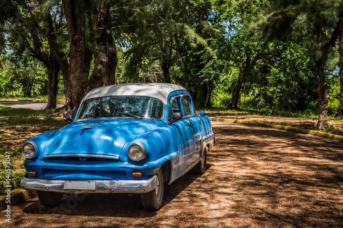 HDR - Amerikanischer blauer Oldtimer parkt unter B  umen in Santa Clara Kuba - Serie Kuba Reportage