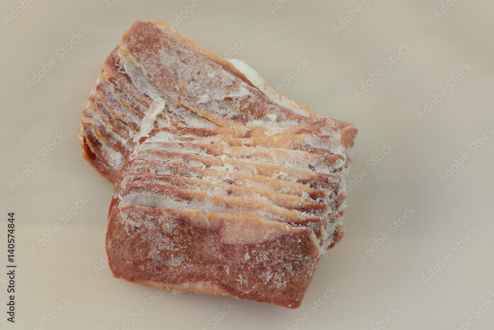 Frozen turkey bacon strips thawing on white plate Frozen turkey bacon strips thawing on white plate