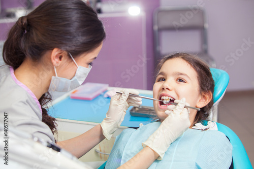 Close-up of pretty little girl opening his mouth wide during treating her teeth by the dentist