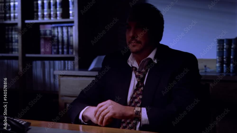 Businessman in a darkened room, looking thoughtful and serious Businessman in a darkened room, looking thoughtful and serious
