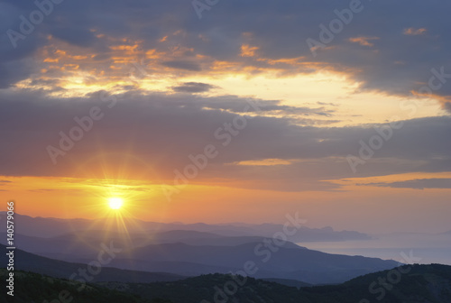 Mountain landscape at sunset. Amazing view from the mountain peak on rocks, low clouds, blue sky and sea in the evening. Colorful nature background.