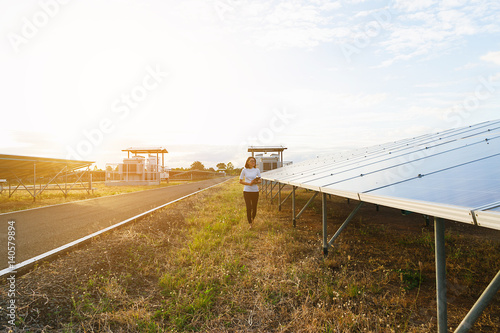 woman engineer working on checking checking status equipment at solar power plant with tablet checklist; woman working on outdoor at solar power plant 