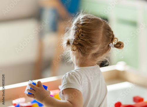 Little cute little girl plays with Geometric figures, indoor