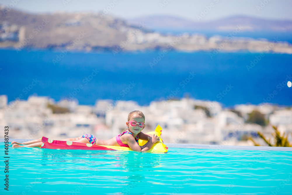 Adorable little girl playing in outdoor swimming pool with beautiful view