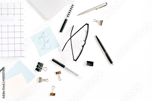 White office desk frame with quote Just Do It and supplies. Laptop, notebook, pen, clips, glasses and office supplies on white background. Flat lay, top view, mockup.