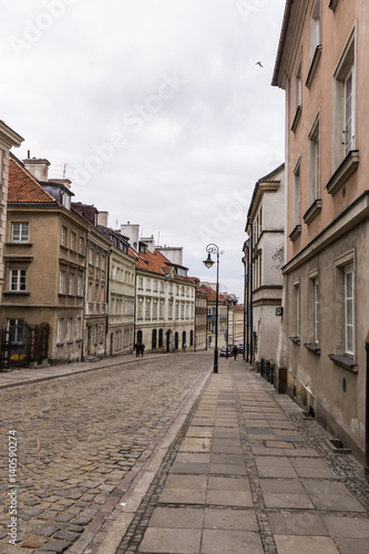 The area of the Old Town in Warsaw  Poland . An old street with nineteenth-century houses  a street lamp and a baroque church.