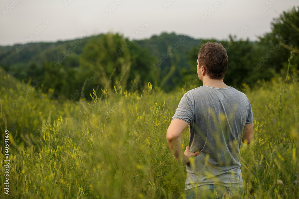 Man standing in the field looks at the beautiful landscape on nature. Copy space for your design