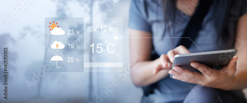 Photos Woman checking up the weather forecast from tablet application