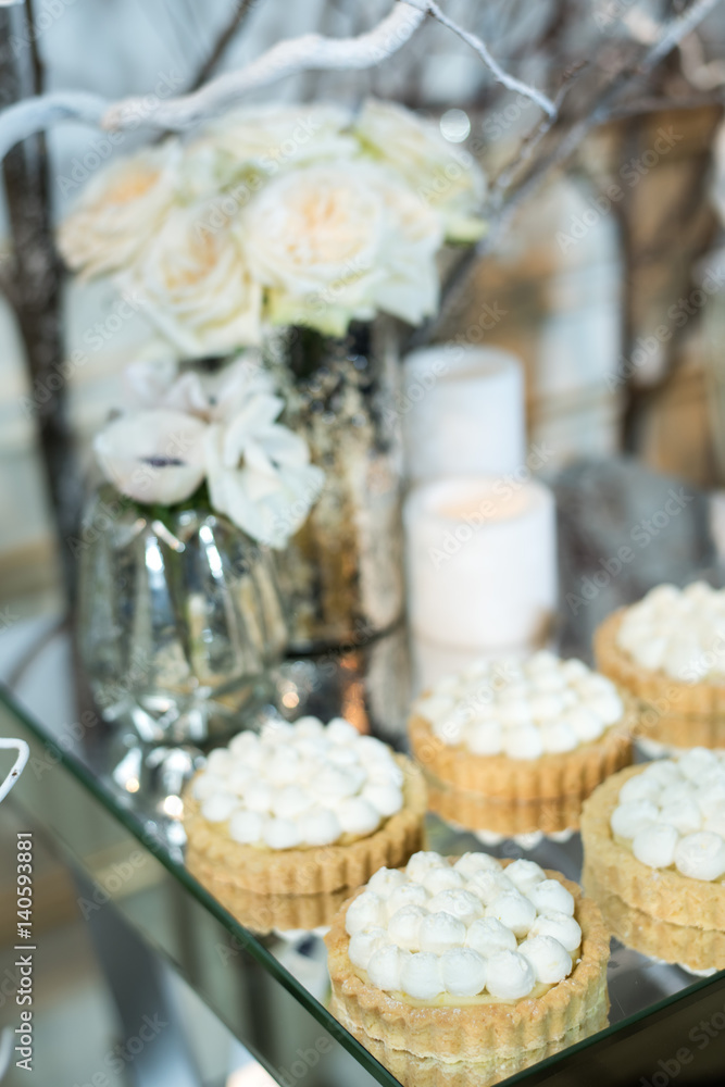Cupcakes with white cream on the table decorated with white flowers and candles Cupcakes with white cream on the table decorated with white flowers and candles
