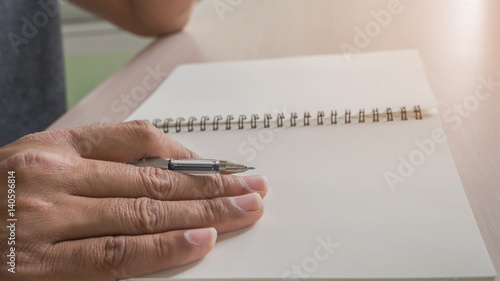 Man hand with pen writing on notebook.