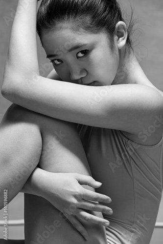 Tired ballet dancer sitting on the gray background