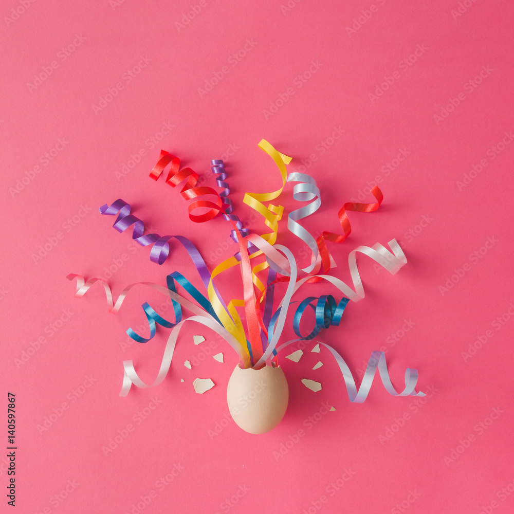 Egg with party streamers on pink background. Easter concept. Flat lay.