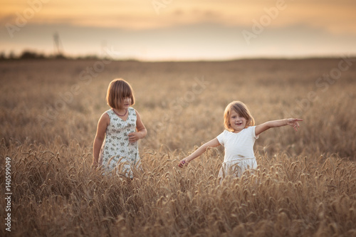 Two emotional sisters girls dance at sunset