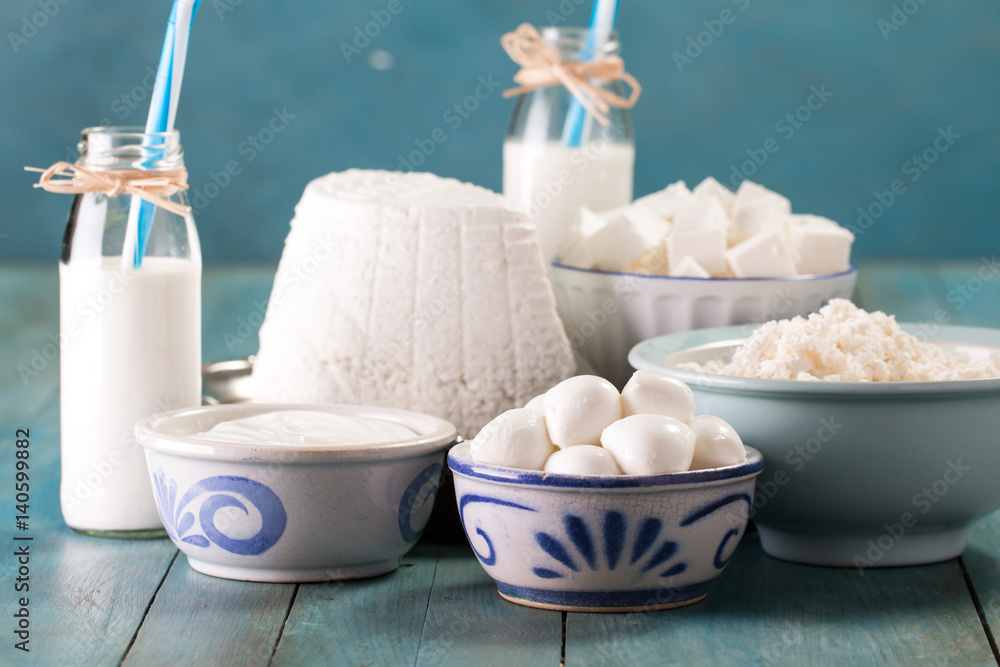 tasty healthy dairy products on a table on a blue background: sour cream, cottage cheese, mozzarella cheese, butter,ricotta and milk in a bottle tasty healthy dairy products on a table on a blue background: sour cream, cottage cheese, mozzarella cheese, butter,ricotta and milk in a bottle