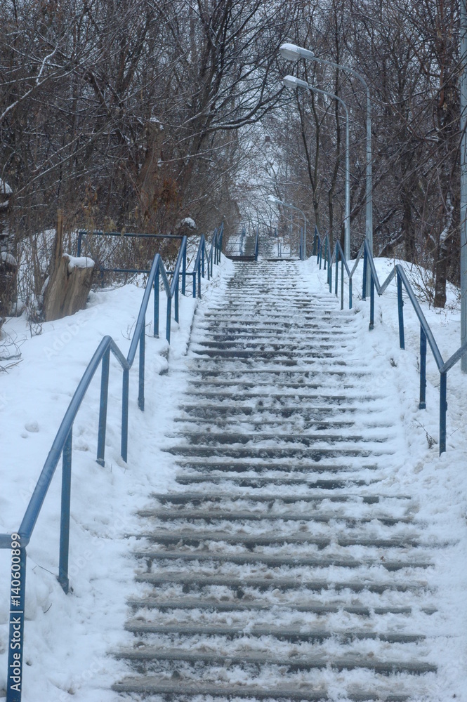 A large snow-covered stairway is up in the park in winter. A large snow-covered stairway is up in the park in winter.