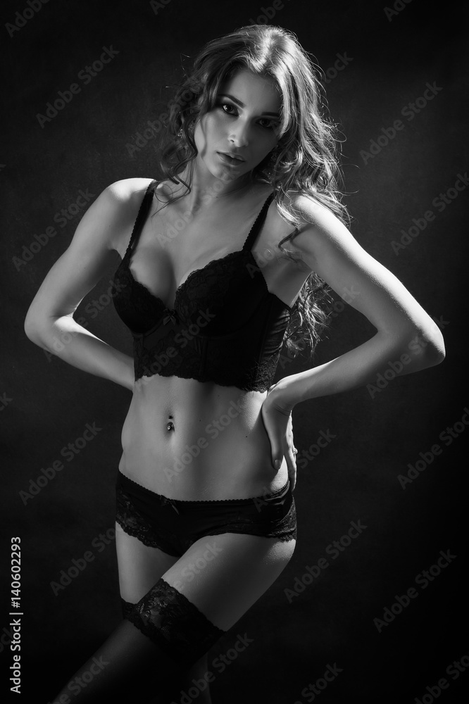 Fototapeta premium beautiful woman show her slim body on black background, monochrome