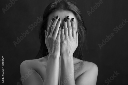 woman cover her face on black background, monochrome