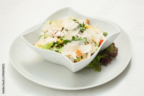 Mixed vegetable salad in a white bowl on white background