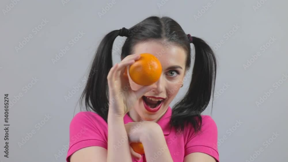 Attractive girl holds up a oranges and laughs Attractive girl holds up a oranges and laughs