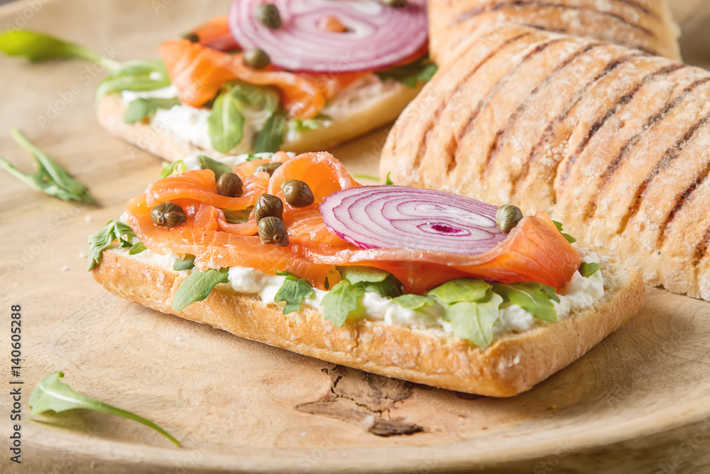 homemade baguette with smoked salmon, onions and arugula. Wooden background.