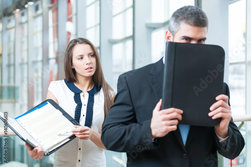 фотографія Businessman hides from coworker behind folder