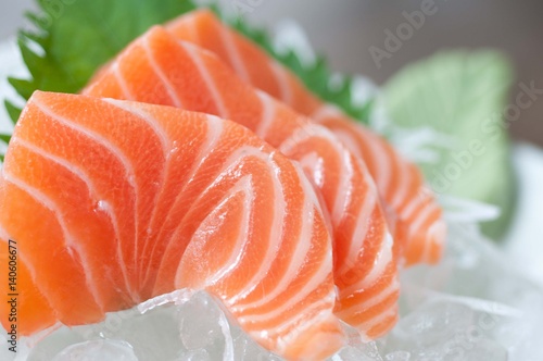 Sliced salmon sashimi served on wooden platter, bokeh background