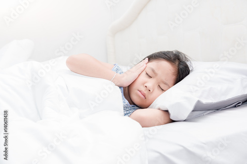 Child lying down suffering from a headache