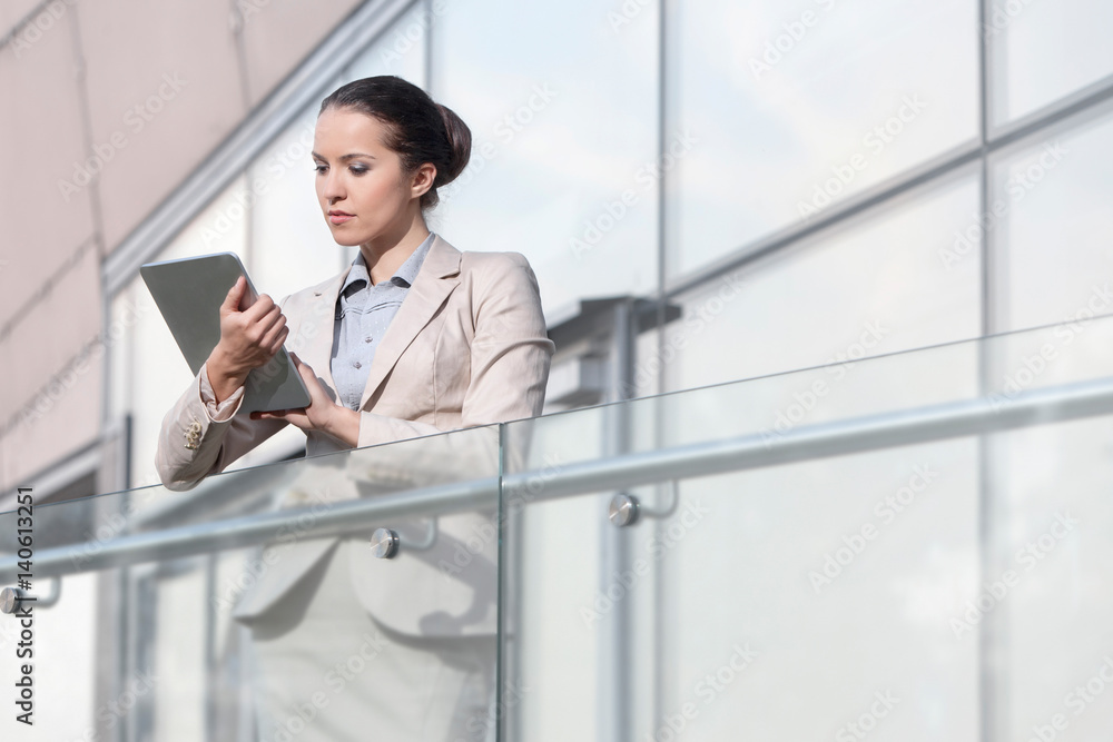 Fototapeta premium Beautiful young businesswoman using digital tablet at office railing