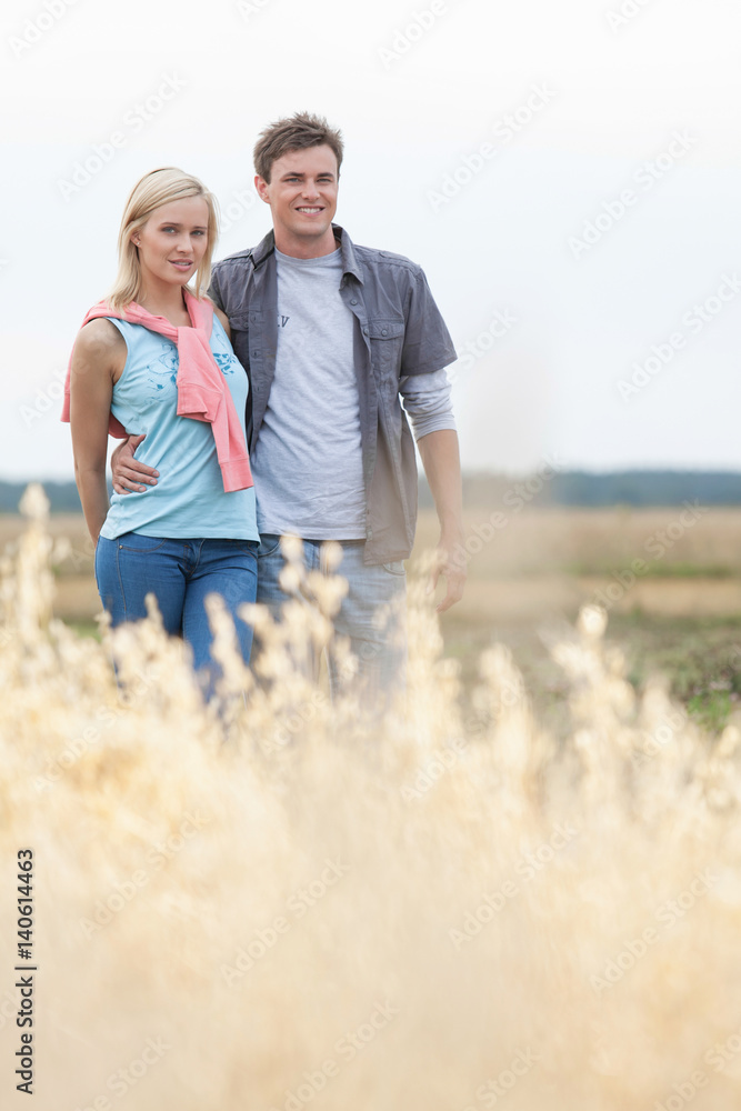 Portrait of young couple standing at field Portrait of young couple standing at field
