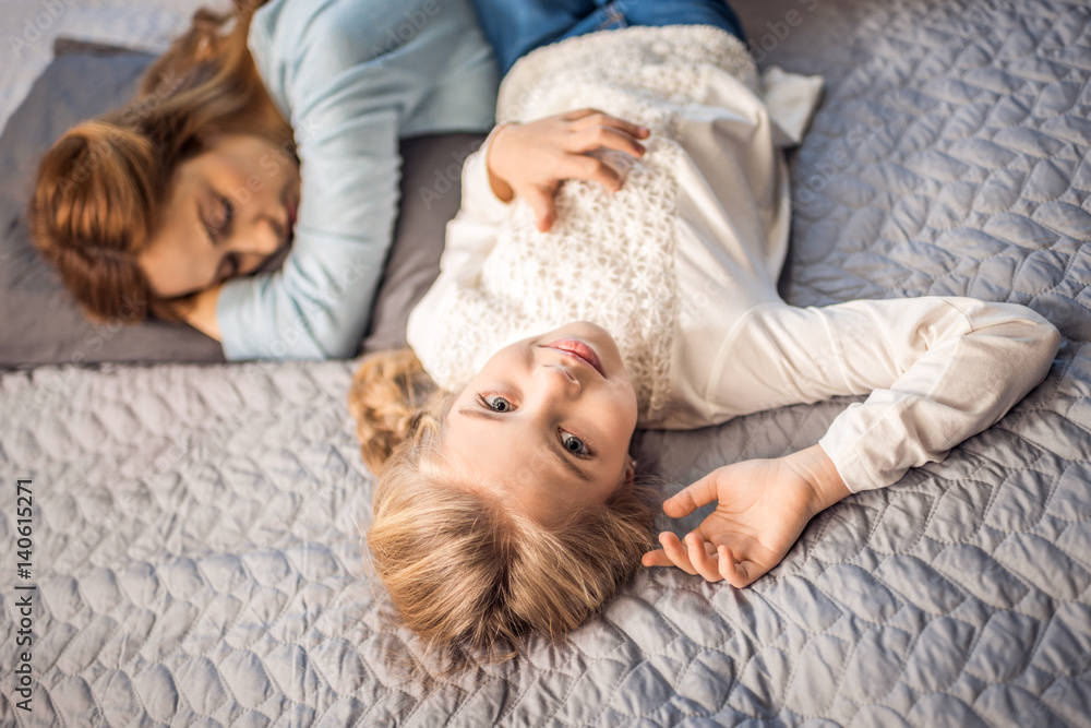 Mother and daughter lying on bed