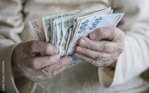 Closeup of wrinkled hands counting turkish lira banknotes