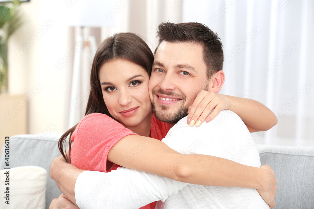 Young couple embracing on sofa in the room Young couple embracing on sofa in the room