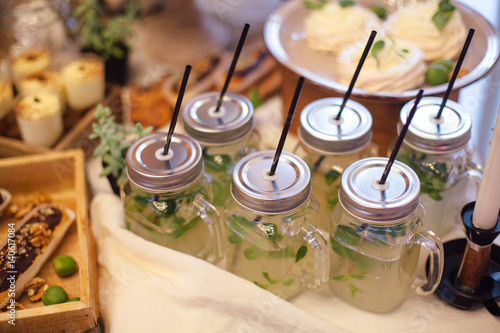 Lemonade with mint in glass jar with straws in area of wedding party