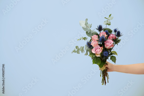 Tablou Canvas Female hand holding beautiful bouquet on light background