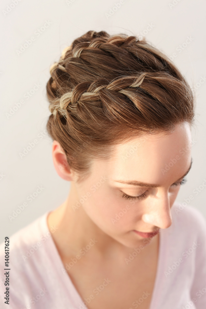 Young beautiful woman with nice braid hairstyle on light background Young beautiful woman with nice braid hairstyle on light background