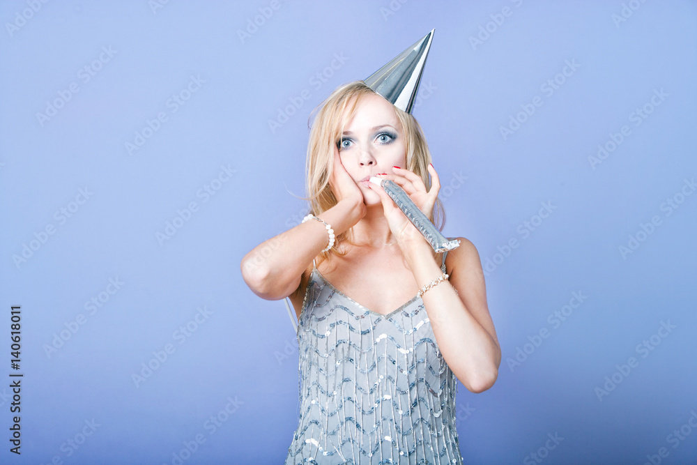 Sexy blonde party girl wearing silver dress and blowing party whistle Sexy blonde party girl wearing silver dress and blowing party whistle