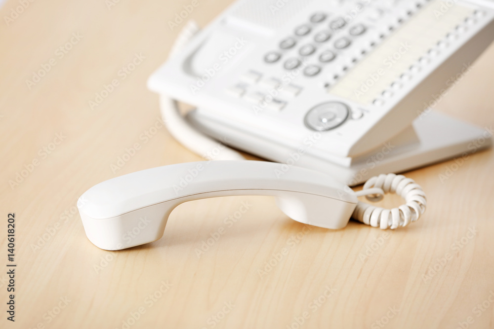 Telephone with picked up receiver on wooden table in office Telephone with picked up receiver on wooden table in office
