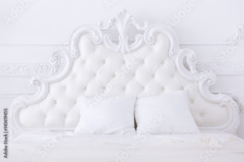 white headboard of a bed in classical style in a light bedroom photo