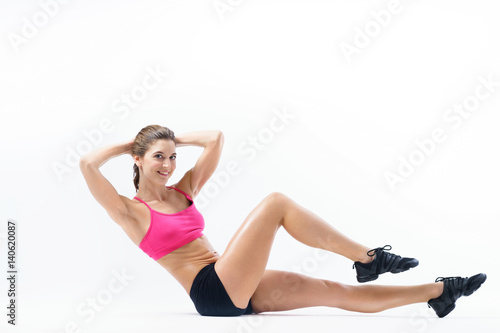 Young attractive tanned slender girl performs sports exercises. © Evgenii Starkov