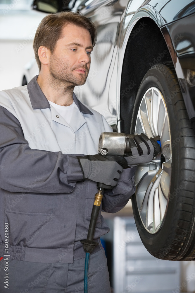 Repairman adjusting car's wheel in workshop