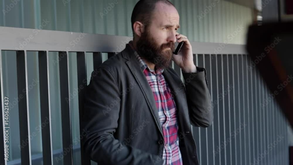 Young trendy man in jacket using phone while standing on stairs. Young trendy man in jacket using phone while standing on stairs.
