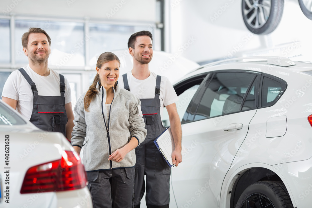 Happy maintenance engineers looking away in automobile repair shop Happy maintenance engineers looking away in automobile repair shop