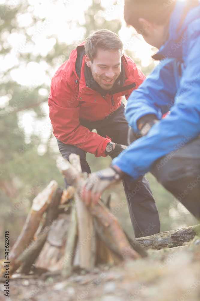 Fototapeta premium Male hikers lighting bonfire in forest