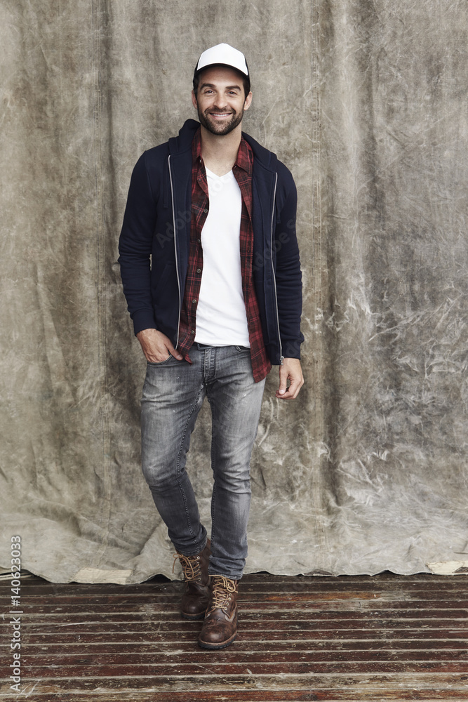 Cap and jeans guy in studio, smiling