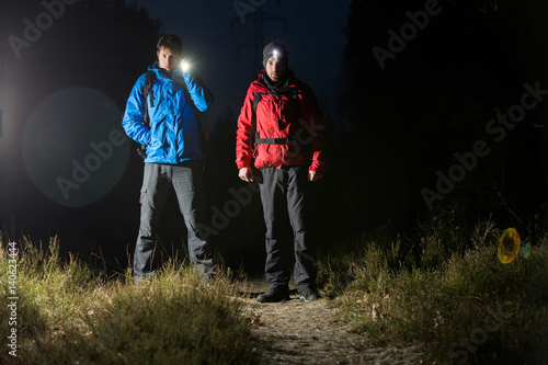 Full length portrait of male hikers with flashlights in field at night