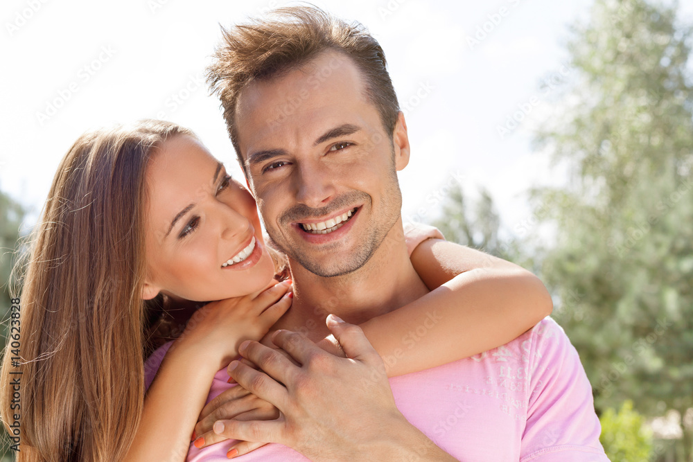 Beautiful young woman embracing man from behind in park Beautiful young woman embracing man from behind in park