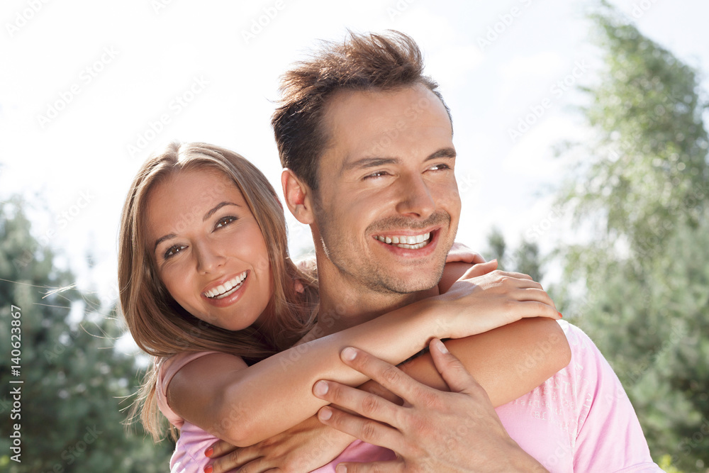 Portrait of beautiful young woman embracing man in summer park Portrait of beautiful young woman embracing man in summer park