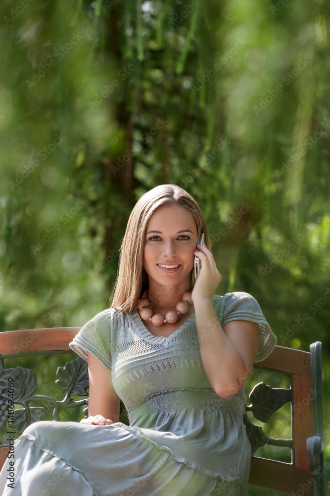 Portrait of beautiful young woman using mobile phone on park bench Portrait of beautiful young woman using mobile phone on park bench